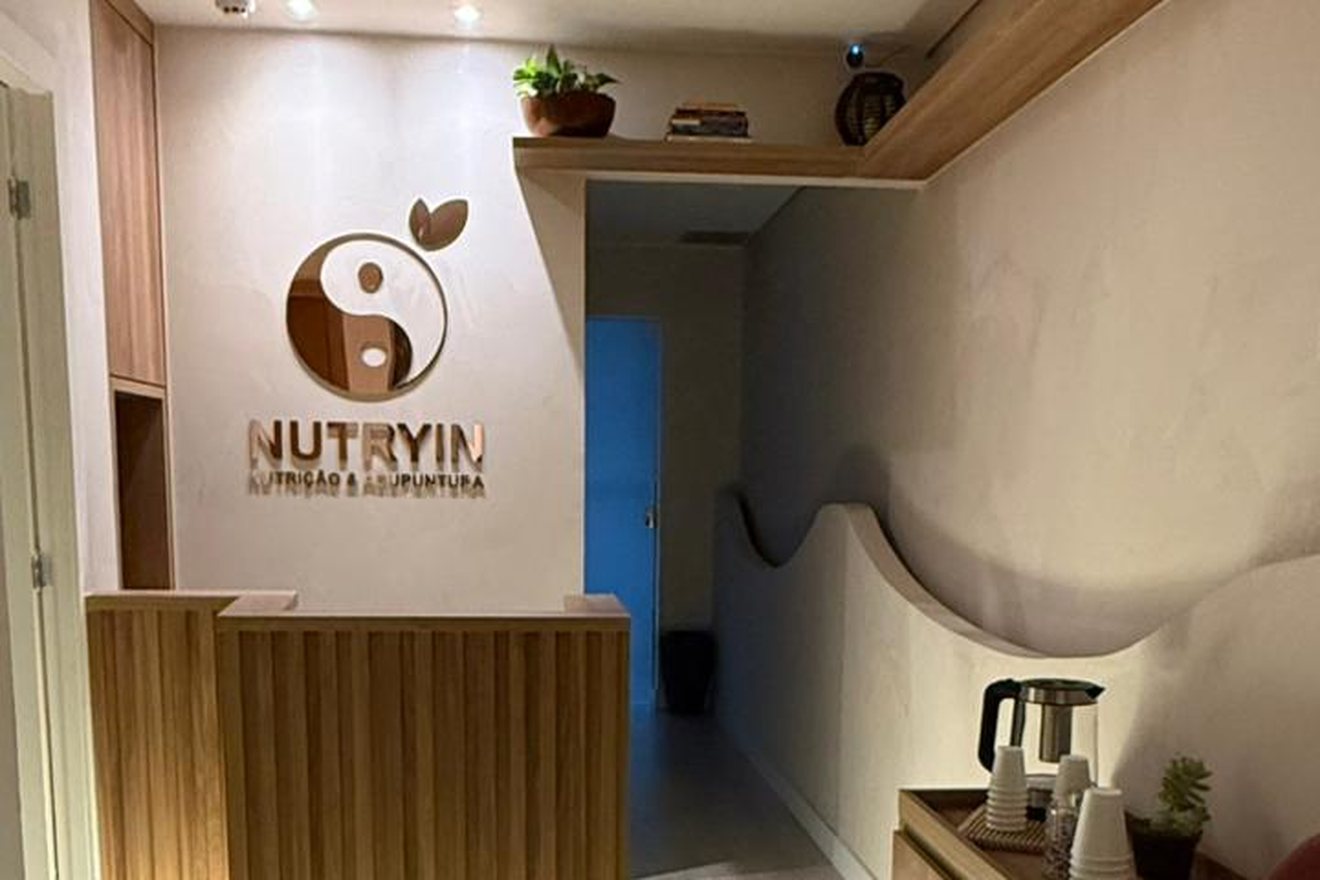 Recepção da Nutryin, com o logo em relevo na parede e o balcão de madeira clara